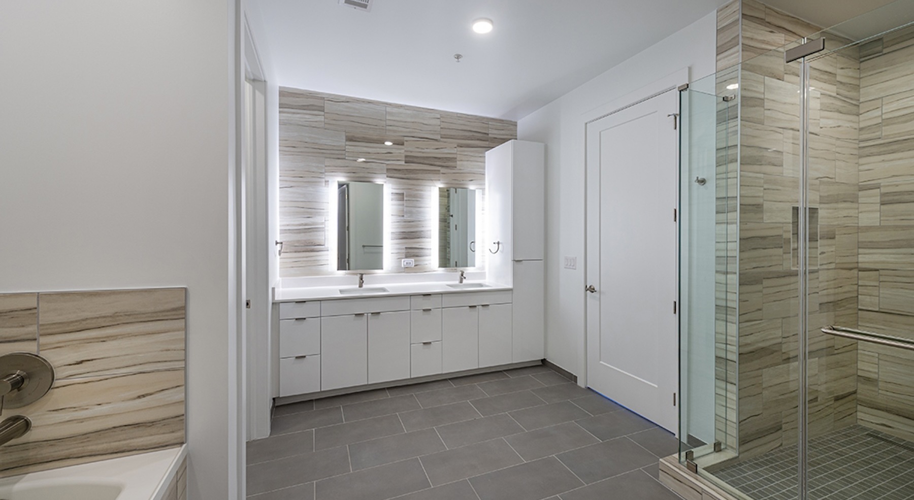 bath with two vanity mirror areas and a walk-in shower
